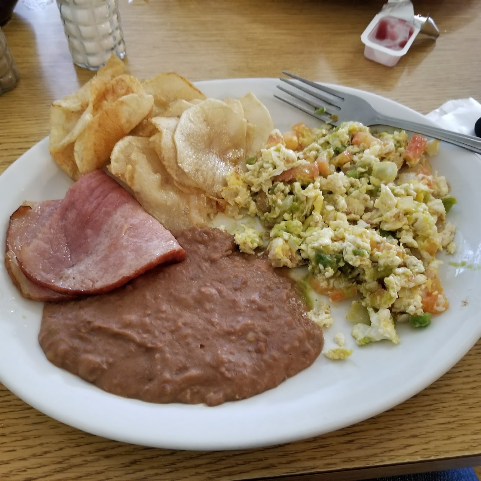 Eggs a la Mexicana plate with ham, chips and refried beans