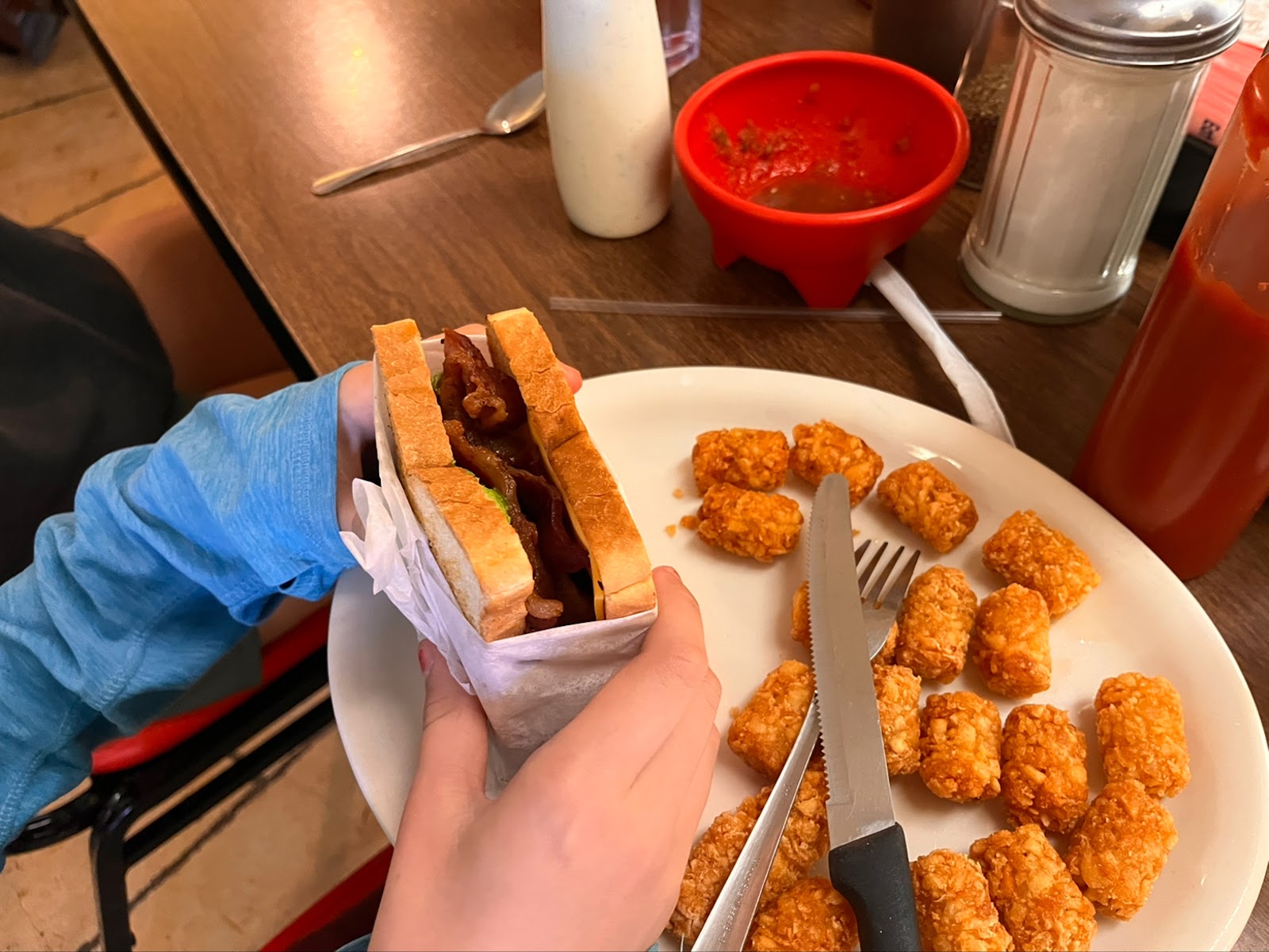 ABC sandwich with avocado, bacon and cheese alongside tater tots