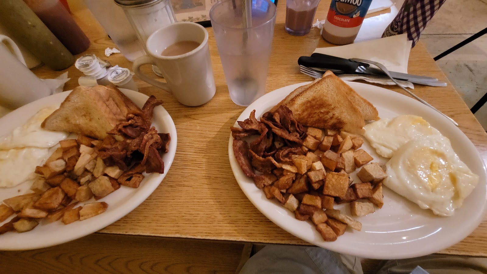 Two full breakfast plates with eggs, bacon, hash browns and toast